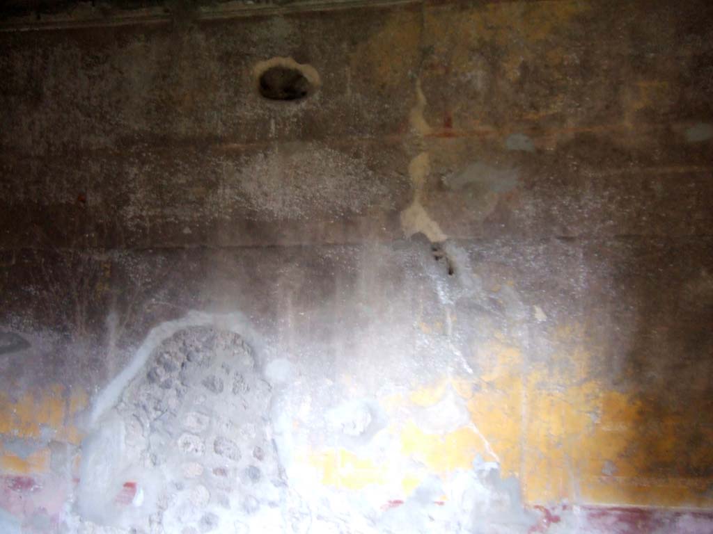 V.2.h Pompeii. December 2005. Room ‘L’, east wall with decoration on a yellow background.
The triclinium had a floor of signinum, and the walls were decorated with panelled yellow backgrounds separated by narrow compartments with garlands.
The zoccolo/dado was of red/purple with painted plants.
It received light from two windows, one in the west wall overlooking the garden, and the other in the south wall looking into room ‘m’.
In the west wall, near to the entrance doorway, was a rectangular niche (height 0.78m width 0.49m). This would have been faced internally with wood on the sides, and at the back it was plastered with the same yellow as the walls.
At the foot of the east wall were two large blocks of limestone, remains of ancient construction.
See Notizie degli Scavi di Antichità, 1896, (p.423) where the triclinium is room ‘g’.
See Mau in Bullettino dell’Instituto di Corrispondenza Archeologica (DAIR), VIII, 1893, (p.14-27)