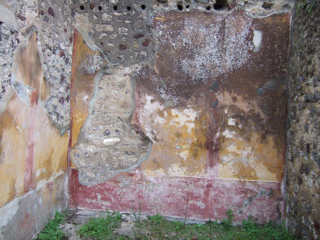 V.2.h Pompeii. December 2005. Room ‘m’, looking towards the east wall with round holes for roof supports.
The zoccolo/dado was red.
The walls were yellow edged with “carpet” borders which are only just visible and separated into three panels by narrow red compartments.