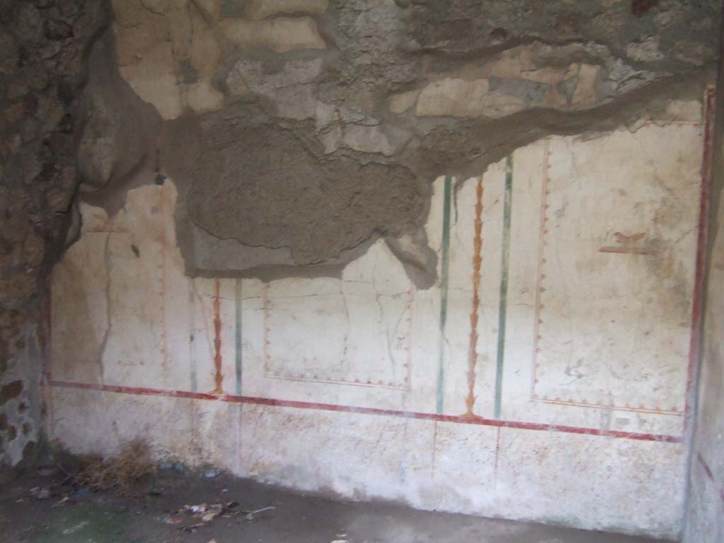 V.2.h Pompeii. December 2005. Cubiculum ‘b’, remains of painted decoration on the north wall.
According to Spano, when excavated the walls of this room were described as having a complete white background.
Each wall was split into three rectangular compartments, separated by yellow candelabra and green bands, and a bird in the centre of each division.
The upper frieze was almost entirely destroyed but was probably decorated with the usual bands and arabesques.
The lower part of the wall was decorated with squares of small specks of various colours, imitating marble.
The floor was of mortar with numerous marble stones set into it.
Found in this room on September 28th 1907 were three bone cylinders perhaps furniture hinges, together with three nails, a ring, and a type of small ferrule, all in bronze.
See Spano in Notizie di Scavi di Antichità, 1910, p.329 where it is referred to as ‘c’.