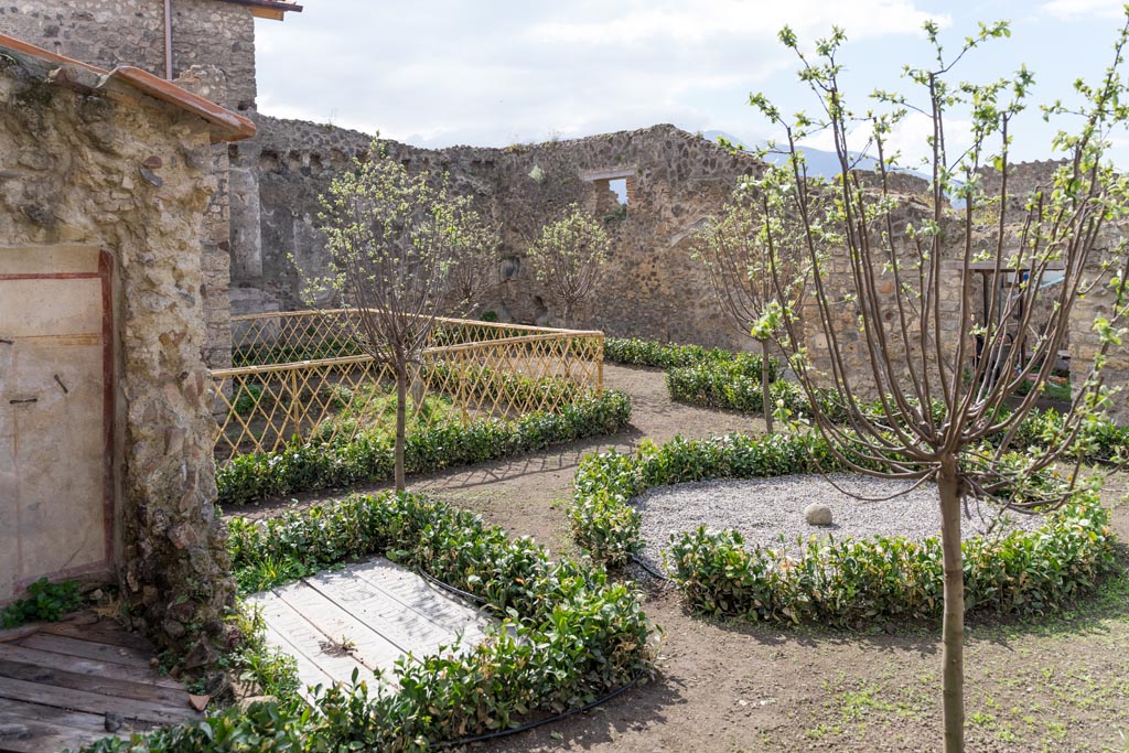 V.2.i Pompeii. March 2023.
Room 12, looking south-west across garden area, from near latrine, on left. Photo courtesy of Johannes Eber.