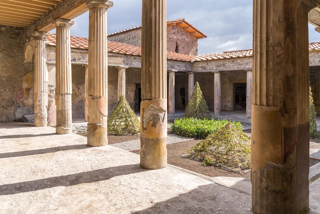 V.2.i Pompeii. March 2023. Looking east along north portico from north-west corner. Photo courtesy of Johannes Eber.
According to Jashemski –
“There was a gutter around the edges of the garden.
In the north gutter there was a lead aqueduct pipe, which coming from the east, divided near the north-west column into two branches.
One was attached to the lower part of the large column and pilaster, the other was directed toward the kitchen and the pool connected with the bath.”
See Jashemski, W. F., 1993. The Gardens of Pompeii, Volume II: Appendices. New York: Caratzas. (p.113).