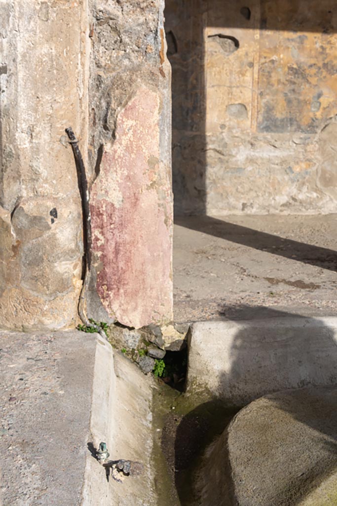 V.2.i Pompeii. January 2024.
Looking east in north-east corner of peristyle, with tap and pipe attached to column/pilaster.
Photo courtesy of Johannes Eber.
