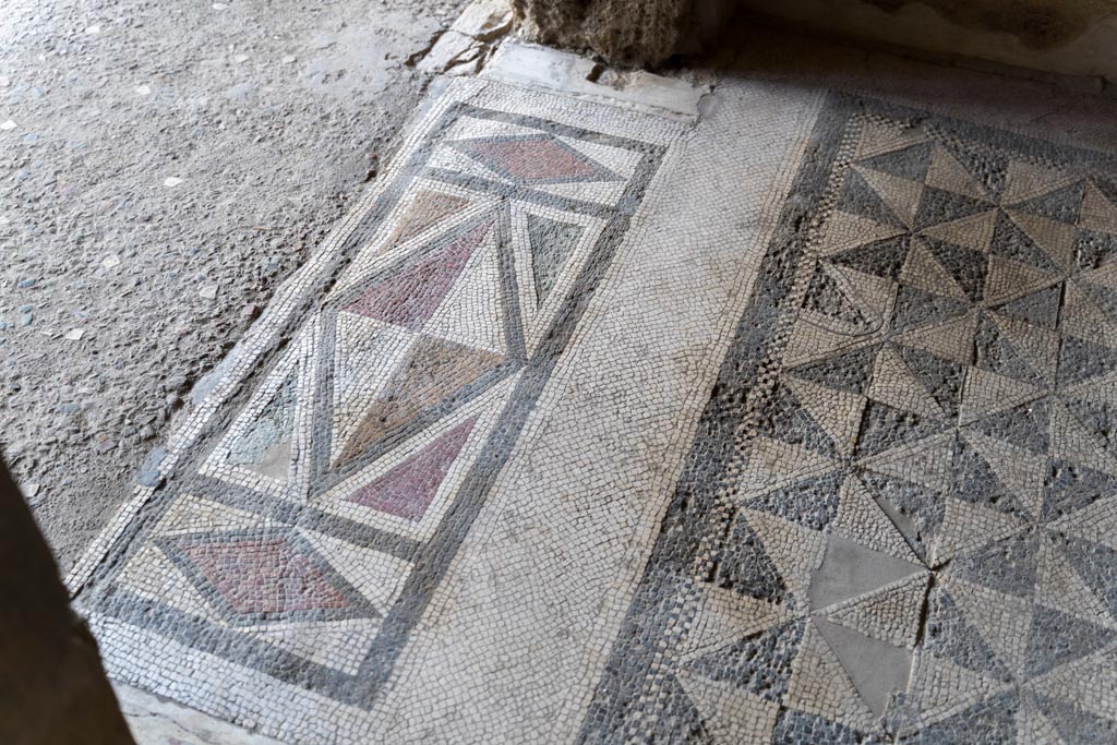 V.2.i Pompeii. March 2023.
Room 18, detail of mosaic doorway threshold, on left, and mosaic flooring, on right. Photo courtesy of Johannes Eber.