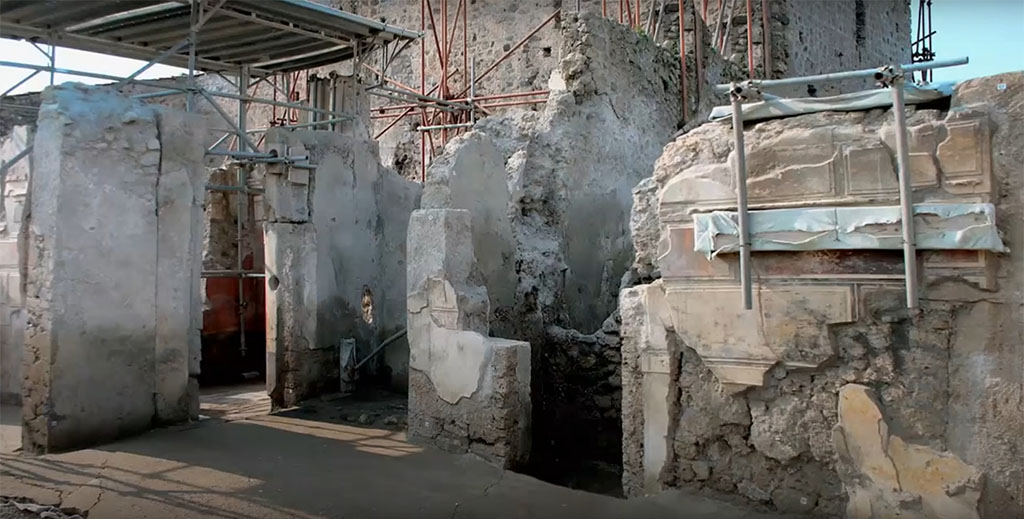 V.2.Pompeii. Casa di Orione. March 2020. Painted stucco blocks on north side of atrium. 
There are two entrances to room A15 with this left one leading to rooms A14 and A16. To the left are rooms A18 and further left room A6 with red painted plaster.
Photograph © Parco Archeologico di Pompei.
