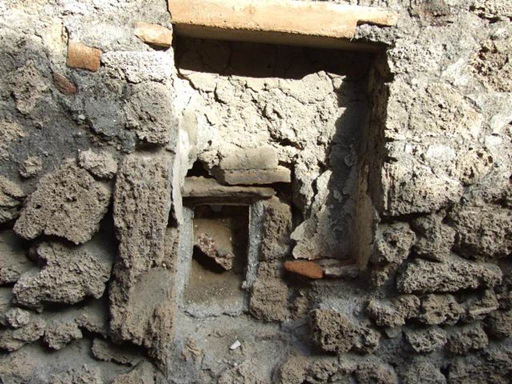 V.2 Pompeii. Casa di Orione. December 2007. Room 11d, rectangular niche.
According to Boyce, Mau described this as a lararium.  
The walls were coated with white stucco, and in the floor were three holes for the bases of statuettes. 
The walls around the niche were covered with the same white stucco.  
In the wall below, a semi-circular receptacle of terracotta was embedded in the floor of an arched niche.  
In the bottom of the terracotta was a round hole, as if for drainage, which suggested a connection with the water supply. 
Today, there is not much remaining.
See Boyce G. K., 1937. Corpus of the Lararia of Pompeii. Rome: MAAR 14.  (no.97 on p. 35)
