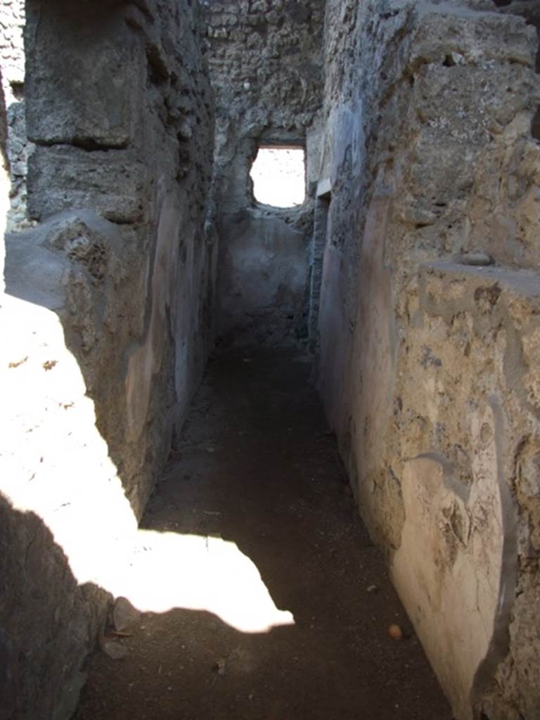 V.3.4 Pompeii. March 2009. Corridor leading east, to small room on the south side.
According to Sogliano, this corridor on the north side of the front room had wooden door-jambs at the entrance. The walls were lined with rough plaster with a high brick plinth.
On the right, immediately upon entering the corridor, he saw a small niche which had side walls clad in wood. Facing it in the left wall was a rectangular window, fitted with the equal of a sill and jambs made of wood. A second window was at the end of the corridor.
A doorway at the end led into a small room or cupboard. See Notizie degli Scavi di Antichit�, 1905, (p. 209)


