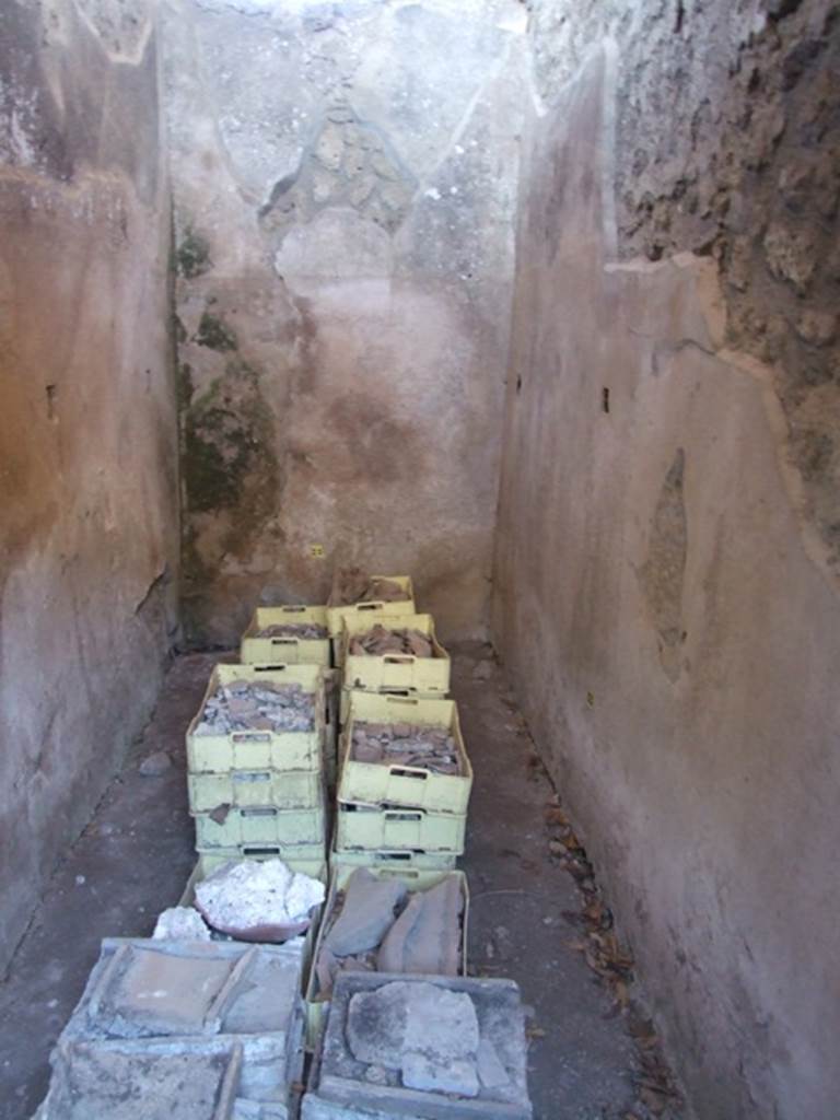 V.3.4 Pompeii. March 2009. Small room with remains of shelving supports. According to Sogliano, the small room on the south side of the end of the corridor was covered with a roof. The roof tilted outwards, and some roof tiles remained in situ. The flooring was of broken brick pieces, and the walls covered with rough plaster, with high brick plinth. Found in the east and west walls, at a height of 1.20m from the flooring, were three square holes for each wall. These holes were decorated with a yellow band around them, and were intended to hold the wooden shelving supports. However as there was no trace of either on the walls, he believed they had not yet been put into place. See Notizie degli Scavi di Antichit�, 1905, (p. 209-10)
