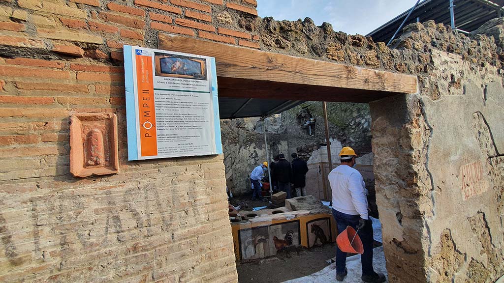 V.3 Pompeii, Thermopolium with painting of nereid. December 2020. Entrance doorway on Vicolo dei Balconi, looking east.
The thermopolium with painting of nereid has a second entrance in the vicolo dei Balconi. 
To the left of this entrance is a terracotta plaque with a phallus. 
Below this is a painted inscription to Caprasium. To the right of the door is a second inscription to Albucium.
V.3 Pompei, Termopolio con dipinto di nereide e anfore. Dicembre 2020. 
Il termopolio ha un secondo ingresso nel vicolo dei Balconi. A sinistra di questo ingresso c'è una placca di terracotta con un fallo. Sotto c'è un'iscrizione dipinta a Caprasium. A destra della porta c'è una seconda iscrizione ad Albucium.
Photograph © Parco Archeologico di Pompei.

