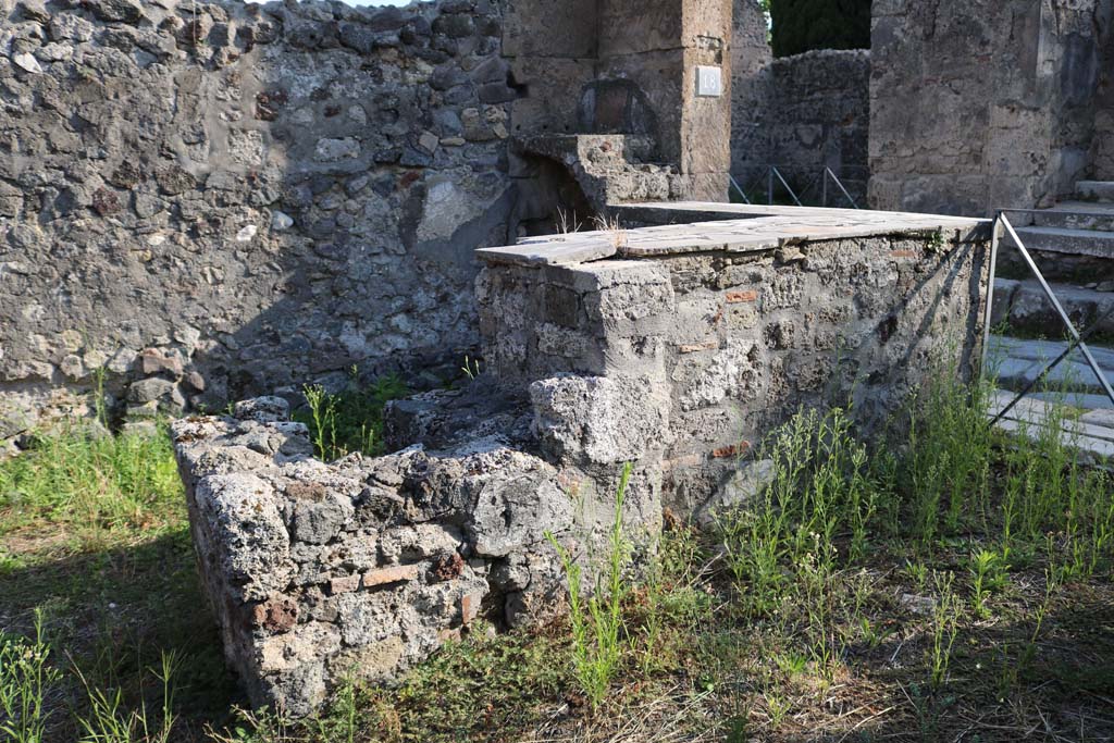 VI.1.18, Pompeii. December 2018.
Looking south to two-sided marble counter with hearth and two-tier shelving. Photo courtesy of Aude Durand.