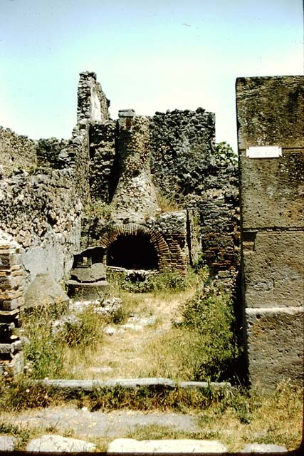 VI.2.6 Pompeii. December 2005. Mill and oven, and doorway to rear room.
According to Boyce, in the north wall of the room behind the oven was a large rectangular niche. See Boyce G. K., 1937. Corpus of the Lararia of Pompeii. Rome: MAAR 14. (p.44, no.140)