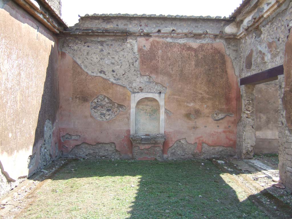 VI.2.22 Pompeii. September 2005. Aedicula niche in south wall of pseudo-peristyle.
On the right is the doorway to the large triclinium.
According to Jashemski, this peristyle garden, excavated in 1811, was enclosed by a portico on the north and part of the east and west sides.
The portico was supported by five columns, red below, fluted and white above.
They were joined by a low wall.
There was an aedicula lararium (2.55m high) in the centre of the south wall.
This once held a beautiful bronze statue of Apollo (Naples Archaeological Museum inv no: 5613).
Dwyer pointed out that the Apollo was not found in the niche, however, but in the north colonnade of the peristyle, according to a report of Soprastante Pasquale Scognamiglio which Dwyer found in the archives of the Soprintendenza at Naples (VIII c8, Apr 3, 1811).
The Apollo was immediately reburied and discovered two days later in the presence of Queen Maria Carolina.
An earlier report of Scognamiglio (Mar 21, 1811) mentioned a niche identical to the one in this house.
But this house became confused with the one next door (VI.2.16/21) which became known as the House of the Apollo, and the statue was said to have been found there. Dwyer points out that the only niche in the garden of VI.2.16/21 is modern, and it is only 0.67m high.
See Jashemski, W. F., 1993. The Gardens of Pompeii, Volume II: Appendices. New York: Caratzas. (p.122-3 and fig 134 for the Bronze Apollo).