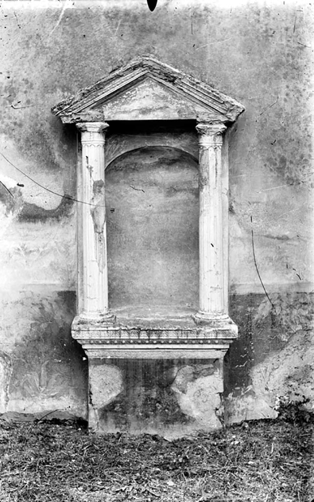 VI.2.22 Pompeii. W.1392. Aedicula niche lararium.
According to Boyce, in the centre of the south wall of the pseudoperistyle stands a fine aedicula.
On a rectangular base painted red, a heavy projecting ledge adorned with triple bands of stucco supported a platform.
On this platform rested the bases of two tall, fluted columns with bases and capitals, all coated with white stucco.
The columns in turn supported a pediment.
The back wall within the aedicula is hollowed out to form a niche, and painted blue.
See Boyce G. K., 1937. Corpus of the Lararia of Pompeii. Rome: MAAR 14. (p.44, and Pl.35,2)
Photo by Tatiana Warscher. Photo © Deutsches Archäologisches Institut, Abteilung Rom, Arkiv.