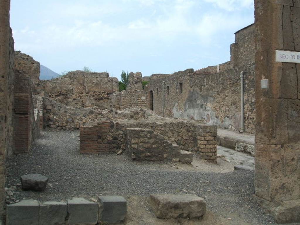 VI.6.4 Pompeii. May 2005. Looking north through entrance towards remains of rear wall with steps to upper floor. On the left is the doorway to a rear room. This bakery was damaged due to the bombing of 1943, when the south-east corner of the atrium of VI.6.1 and the nearby workshops were hit. On the right can be seen the doorway at VI.6.5.