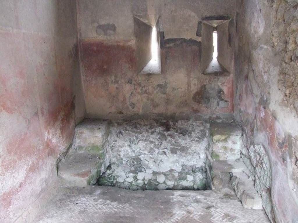 VI.9.6 Pompeii. March 2009. Room 18, large latrine near east wall of kitchen and latrine. According to Hobson, this latrine is just over one metre wide and would have had more than one seat. This would allow for “private” socialisation. See Hobson, B., 2009. Latrinae et foricae: Toilets in the Roman World. London; Duckworth. (p.80) He also states that this latrine possibly would have seated two or three persons. It had a high decorated dado, painted red, with yellow panels but without motifs. In the area above the dado, a garland of flowers is visible. The floor is a mixture of herringbone and oval tiling. See Hobson, B., 2009. Latrinae et foricae: Toilets in the Roman World. London; Duckworth. (p.86 and fig.110)