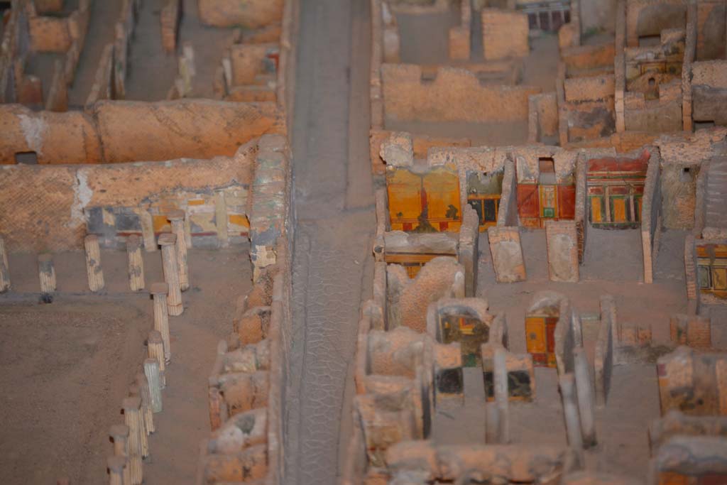 VI.11.9/10 Pompeii. July 2017. Looking west along Vicolo del Mercurio, with VI.12, House of the Faun, on left.
On the right is the south-west corner of atrium 3 (of VI.11.9), with the west wall of the entrance corridor, just visible.
In the corner is the west wall of room 5, with room 4 next to it. 
The doorway to room 6 leads into the room with red/yellow/green west wall, followed by west ala 7. 
Room 8, the area under the stairs, is the undecorated area next to it. 
From cork model in Naples Archaeological Museum.
Foto Annette Haug, ERC Grant 681269 D�COR.
