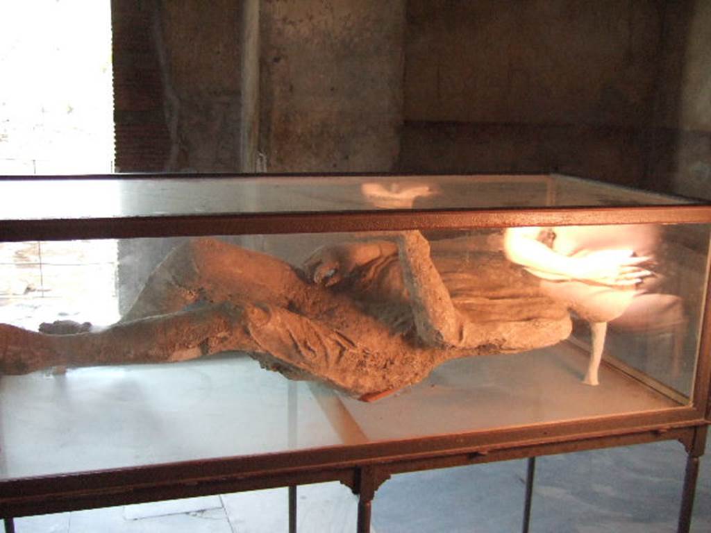 Plaster cast of a supine man with arms and legs slightly contracted, wrapped in a cloak.
Found 23rd April 1875 in NE corner of VI.14 in middle of Via Stabiana, four metres above ground level in the ash layer.
He was found next to the woman with her tunic raised over her head.
When photographed, this was on display in VII.1.8, the Stabian Baths, men’s changing room.
See SSANP: Boscoreale Antiquarium exhibition catalogue: The Casts, 5 March – 20 December 2010. (p.6 and 7)
See Garcia y Garcia, L., 2006. Danni di guerra a Pompei. Rome: L’Erma di Bretschneider. (p.193, Figs 448-9).
September 2005.
