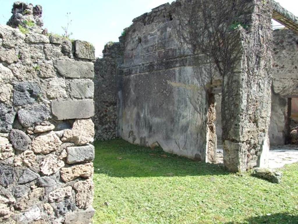 VI.15.5 Pompeii. March 2009. Doorway to room 24, oecus. South wall, with small door into tablinum. According to NdS, this room was a cubiculum and had a floor (�alla veneziana�) and was decorated in the First Style. On the south wall was the remaining decoration of a previous time showing stucco ashlars. Afterwards, a decoration of yellow panels divided by white areas with candelabra was substituted. The dado was on a black background with the usual concepts of marsh plants. See Notizie degli Scavi, January 1897, (p.27)
