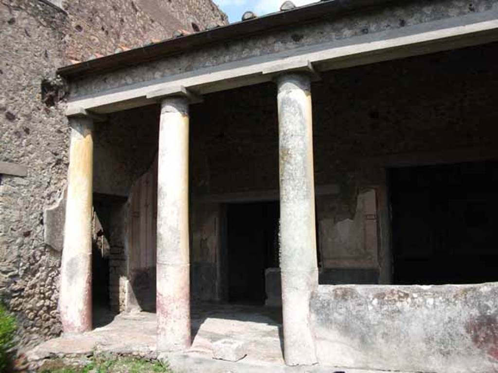VI.15.8 Pompeii. May 2010. Looking north-east from garden towards portico. Doorways to atrium, room leading to VI.15.7 and doorway to oecus. According to Jashemski, the peristyle garden to the left of the atrium originally had a portico on the east side. It was supported by five stucco-covered brick columns, two of which were engaged, yellow above, red below. Of the four spaces between the columns, two were later left open; the third was closed by a low masonry wall. The fourth was incorporated into the west wall of the small room built to the south of the portico. See Jashemski, W. F., 1993. The Gardens of Pompeii, Volume II: Appendices. New York: Caratzas. (p.157)