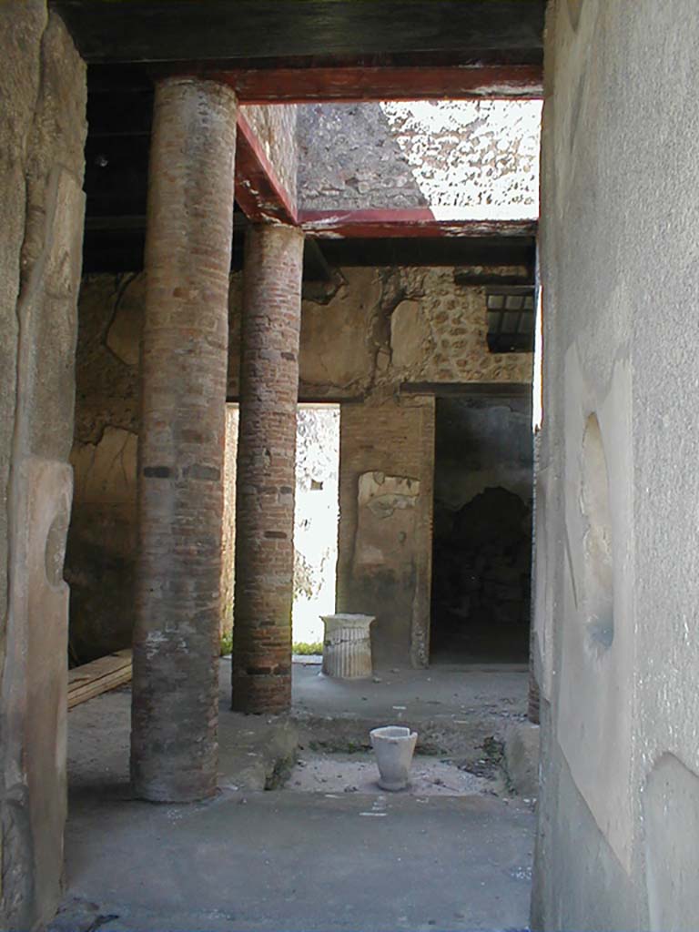 VI.15.9 Pompeii. September 2004. Entrance corridor, looking west to atrium.
According to Richardson, this tiny atrium house had a very efficient design.
The atrium is entered by short fauces flanked by cubicula with windows to the street.
The atrium is almost square, Tetrastyle with columns of naked brick that supported a second floor.
The second floor was a gallery lit by large rectangular windows into the compluvium well.
It was accessible by a small staircase against the north wall of the atrium.
Although it must have made the atrium rather dark, it made living space available over the atrium, as well as over the cubicula at the front of the house.
On the far side of the atrium, opened an ample triclinium and the service area.
This service area in the south-west corner of the house was lit by a second light-well and had a second storey of its own, possibly just a loft for storage.
See Notizie degli Scavi di Antichit�, 1897, 38-39, 62-64.
See Richardson, L., 1988. Pompeii: An Architectural History. Baltimore: John Hopkins University Press. (p.345-6)
(Note � the staircase is actually against the south wall of the atrium)
