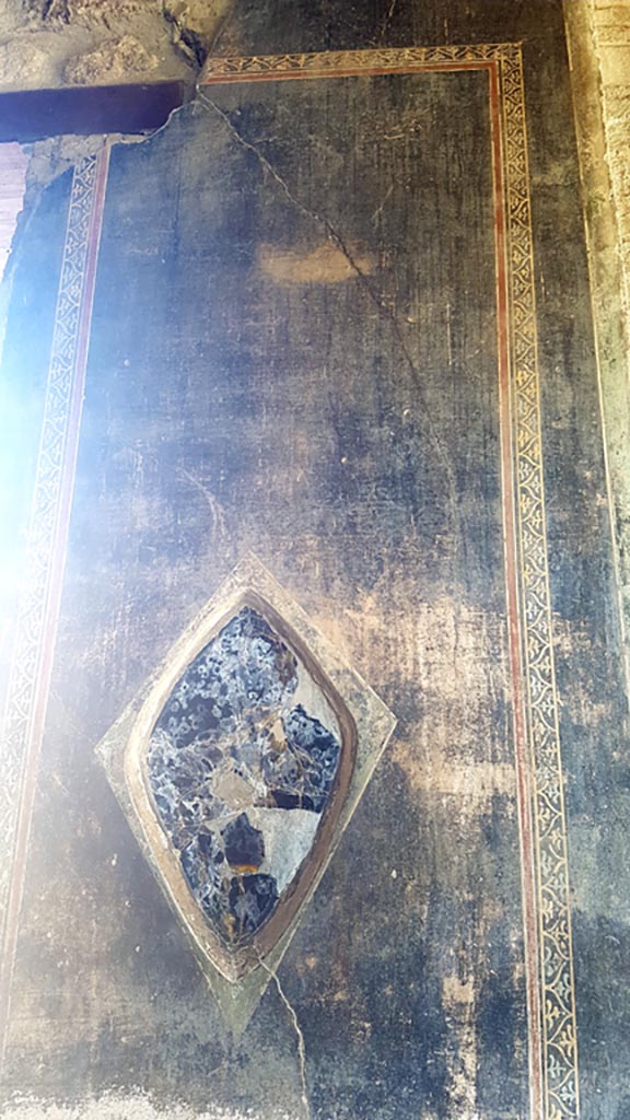 VI.16.7 Pompeii. August 2023.
Wall decoration and obsidian mirror in north-east corner of portico.
Photo courtesy of Maribel Velasco.