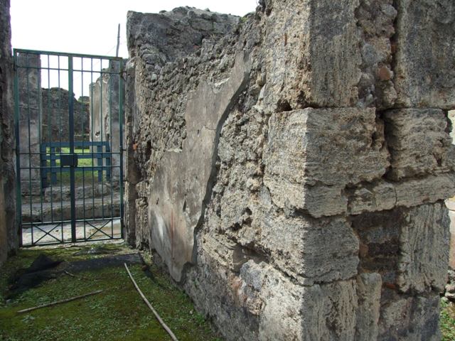 VI.16.27 Pompeii. March 2009. Room 16, recess in south wall of atrium.
According to Boyce, the doorway that led from the atrium to the peristyle was walled up, leaving a shallow recess in the south wall.
Within this recess, in the upper left corner, a white panel was marked off by green stripes on both sides. The figure of Jupiter was painted on the panel. He was seated upon a throne, leaning his forehead against his left hand, through the bend of this arm passed a long sceptre.
The lower end of the sceptre rested on the ground., in his right hand he held the thunderbolt. His feet were placed on a footstool and to its left stood an eagle. In the wall below the panel were embedded two broken tiles, one horizontal, the second perpendicular to the first at its west end. The wall space between the painting of Jupiter and the two tiles was decorated with plants painted on a yellow background. The horizontal tile may have served as a shelf for offerings, but the purpose of the two tiles was not clear. Found near the shrine was a terracotta votive altar. Not. Scavi, 1908, 184. See Boyce G. K., 1937. Corpus of the Lararia of Pompeii. Rome: MAAR 14. (p.59, no.226)