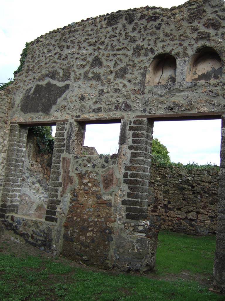 VI.16.32 Pompeii. December 2005.
Room B, east wall of atrium with doorway to room F, garden area with niches above.
According to NdS, in the north-east corner of the atrium was a low masonry wall, on which there was a second smaller one.
Sogliano seemed to think he could see the void in which the end of a wooden ladder would have been fixed.
The wooden ladder would have leaned against the north wall and given access to an upper floor.
See Notizie degli Scavi di Antichità, 1908, (p.287)
To the left and straight ahead in the east wall were two large windows that gave onto garden F, between them was a doorway to the garden.
Later however, the window on the left and the doorway were bricked up, and the window on the right was changed into the doorway.
The garden F was open and uncovered.