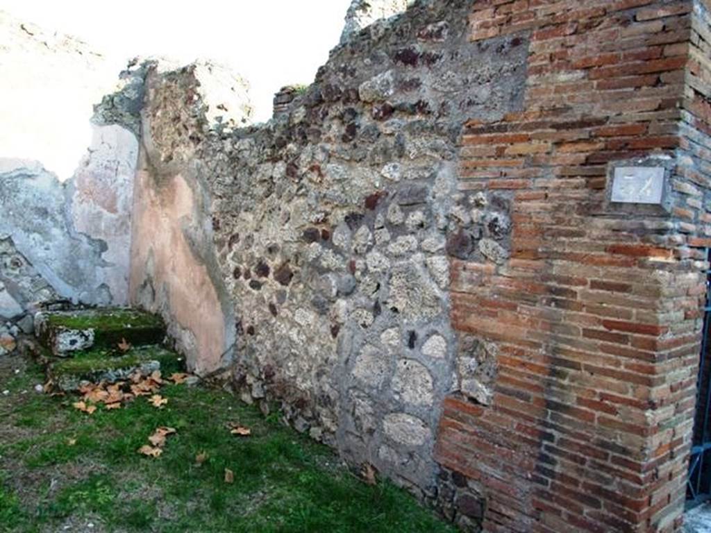 VI.16.34 Pompeii. December 2007. South wall. The shop had a high dado of brick plaster, divided into large panels, by means of vertical red bands. In the centre of each panel was seen the representation of a plant with a very high stem. In the south-east corner is a rise of masonry with two steps, on which rested a wooden ladder leading to the upper floor.
The imprint of the ladder can be seen on the east wall. The floor was of coarse cocciopesto.
