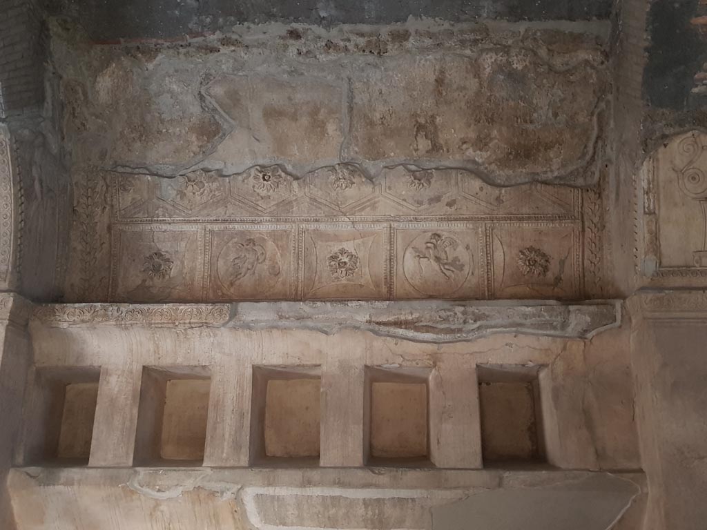 VII.1.8 Pompeii. October 2022.
Centre of south wall, stucco decoration above niches for belongings in men’s changing room 2. Photo courtesy of Klaus Heese.