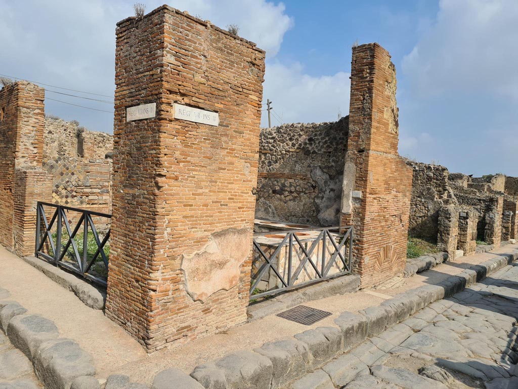 VII.2.33 Pompeii. October 2023. Looking north to entrance doorway on north side of Via degli Augustali, in centre.
On the left is the other entrance at VII.2.32 in Vicolo Storto. Photo courtesy of Klaus Heese.
