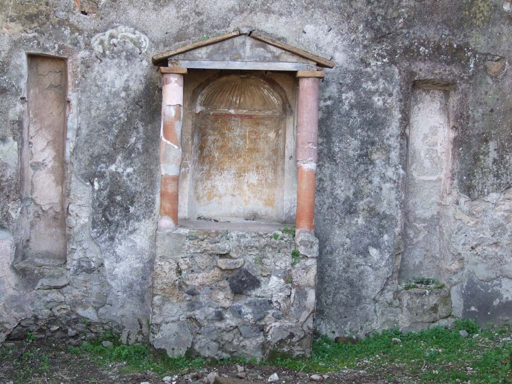 VII.3.6 Pompeii. December 2006. According to Boyce, above a rectangular podium stood two columns coated with red stucco.
These supported the roof with pediment.
The semi-circular niche in the rear wall had its vaulted ceiling adorned with a stucco shell.
The walls of the niche were painted orange and on each side of the niche was a stucco pilaster.
A large marble statuette of Venus Anadyomene was found in the aedicula.
On either side of the aedicula are two long vertical slits, Fiorelli suggested they may have held candelabra.
See Boyce G. K., 1937. Corpus of the Lararia of Pompeii. Rome: MAAR 14. (p. 63, no: 259 and pl. 36, 1)