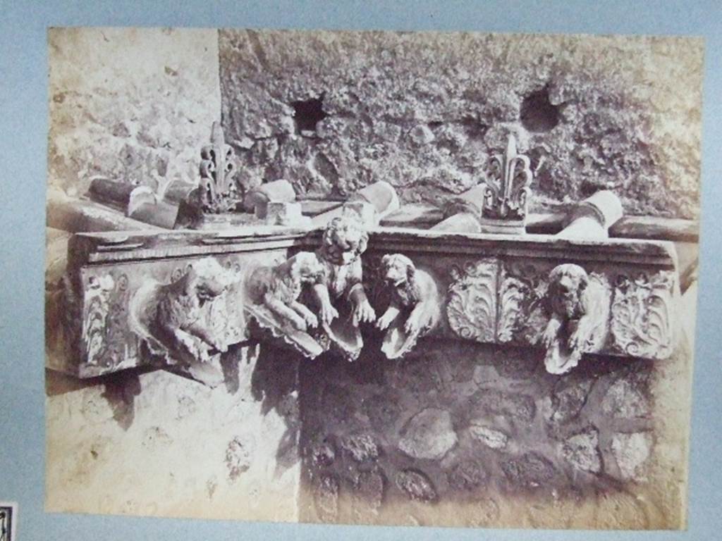�Cornice in terracotta of a Compluvium preserved at Pompeii�.  
Old photograph courtesy of Society of Antiquaries, Fox Collection.
These are Grondaia or rainwater spouts that fed rainwater from the Compluvium in the roof to the Impluvium below.   These were reconstructed and displayed during the 19th century in VII.4.15/16 before the Antiquarium was opened. Mau says they were originally from a House near the Porta Marina,  The plan provided by Mau can be used to identify the house as VII.16.12/15 the House of Umbricius Scaurus. See Mau, A., 1907, translated by Kelsey F. W. Pompeii: Its Life and Art. New York: Macmillan. (p.251, p.253, p.298).