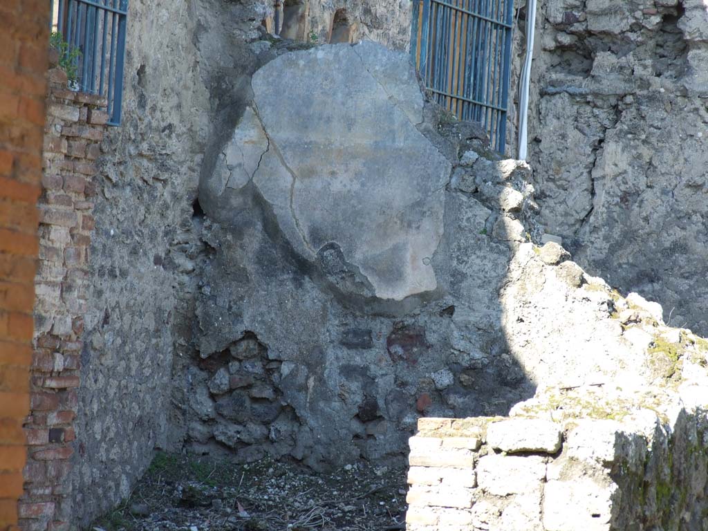 VII.4.25 Pompeii. September 2005. Doorways from VII.4.24 and VII.4.25 to rear rooms. According to Boyce, on the west wall of the kitchen above the hearth, was a Lararium painting in two zones on a white background. It showed the Genius pouring a libation upon an altar. On each side of him was a Lar in a blue tunic and red pallium.
Instead of the customary serpents, the lower zone was filled with a second sacrificial scene, but only the popa remains. He held a knife in his right hand and held a hog with his left. The hog was adorned with a red band around its belly and a garland. See Boyce G. K., 1937. Corpus of the Lararia of Pompeii. Rome: MAAR 14.(p.65, no.272)
According to Garcia y Garcia, all the rear part of this dwelling were damaged by the bombing in September 1943. Demolition of the atrium, fauces and two other rooms in this area occurred, including the falling of the painted fourth style plaster. See Garcia y Garcia, L., 2006. Danni di guerra a Pompei. Rome: L’Erma di Bretschneider. (p. 97)
According to Frohlich, only slight faded traces of the lararium painting remain. See Fröhlich, T., 1991. Lararien und Fassadenbilder in den Vesuvstädten. Mainz: von Zabern. (p.286, L84)
