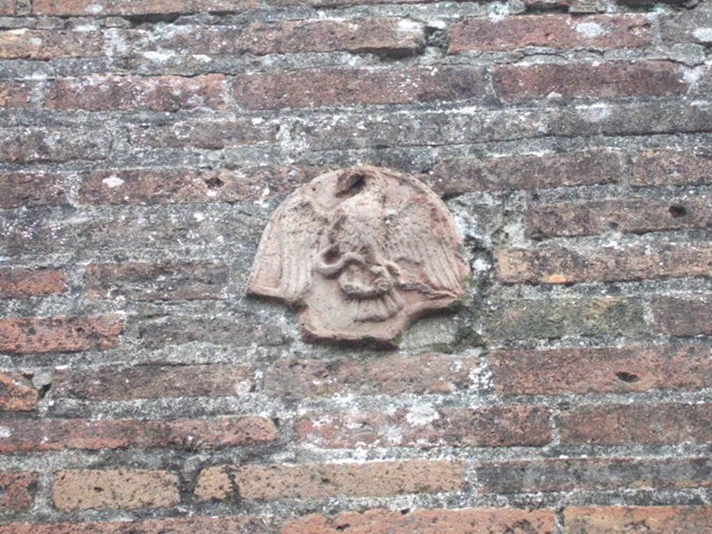 VII.4.56 Pompeii. December 2005. Terracotta plaque with eagle, on wall on east side of entrance. In May 1831, found painted in red and under the plaque of the eagle with a serpent in his claws, was the graffito �
Popidium  Secundum aed(ilem)    [CIL IV 285]
See Pagano, M. and Prisciandaro, R., 2006. Studio sulle provenienze degli oggetti rinvenuti negli scavi borbonici del regno di Napoli. Naples, Nicola Longobardi. 
(p. 145)

