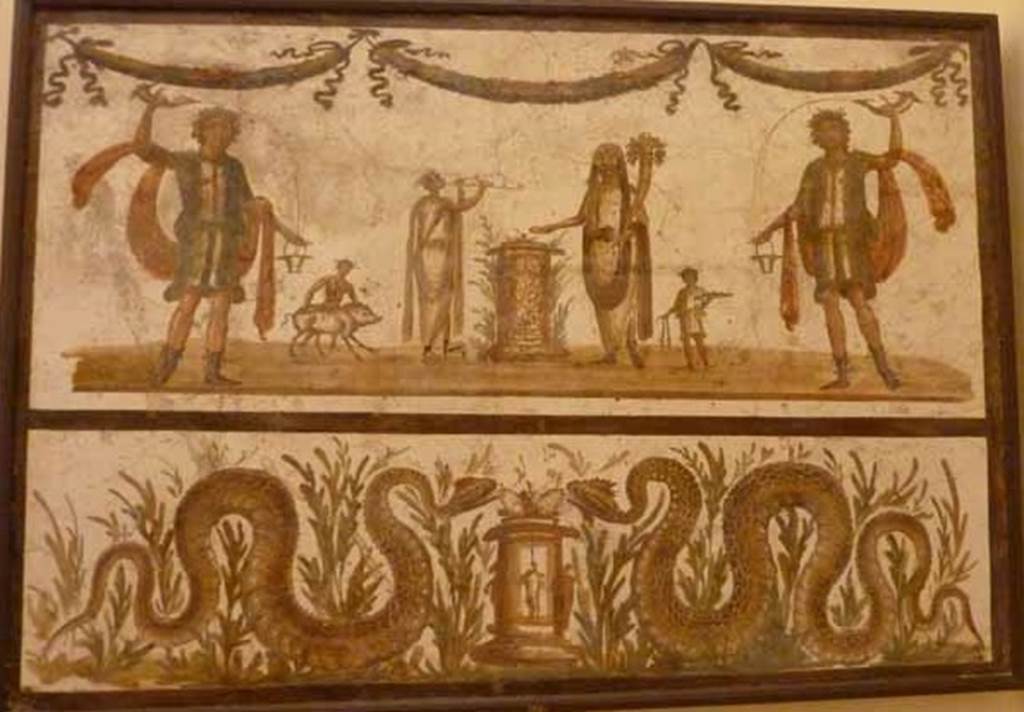 VII.6.38 Pompeii. May 2010. Lararium painting. The upper part has an offering scene. A round altar is in the centre. The offering Genius has a small camillus helping on his right. On the other side of the altar is the tibicen with a popa assisting with a small pig. The scene is flanked on either side by a large lar. Above the scene are three garlands. The lower part has two serpents, in plants, approaching a second round altar, one from either side. Fröhlich says this as found Reg. VII or VIII.
See Fröhlich, T., 1991. Lararien und Fassadenbilder in den Vesuvstädten. Mainz: von Zabern. (L98, T: 10,2).
Pagano and Prisciandaro show this as being from VII.6.38.
See Pagano, M., and Prisciandaro, R., 2006. Studio sulle provenienze degli oggetti rinvenuti negli scavi borbonici del regno di Napoli. Naples : Nicola Longobardi. (p.39).
Now in Naples Archaeological Museum. Inventory number: 8905.