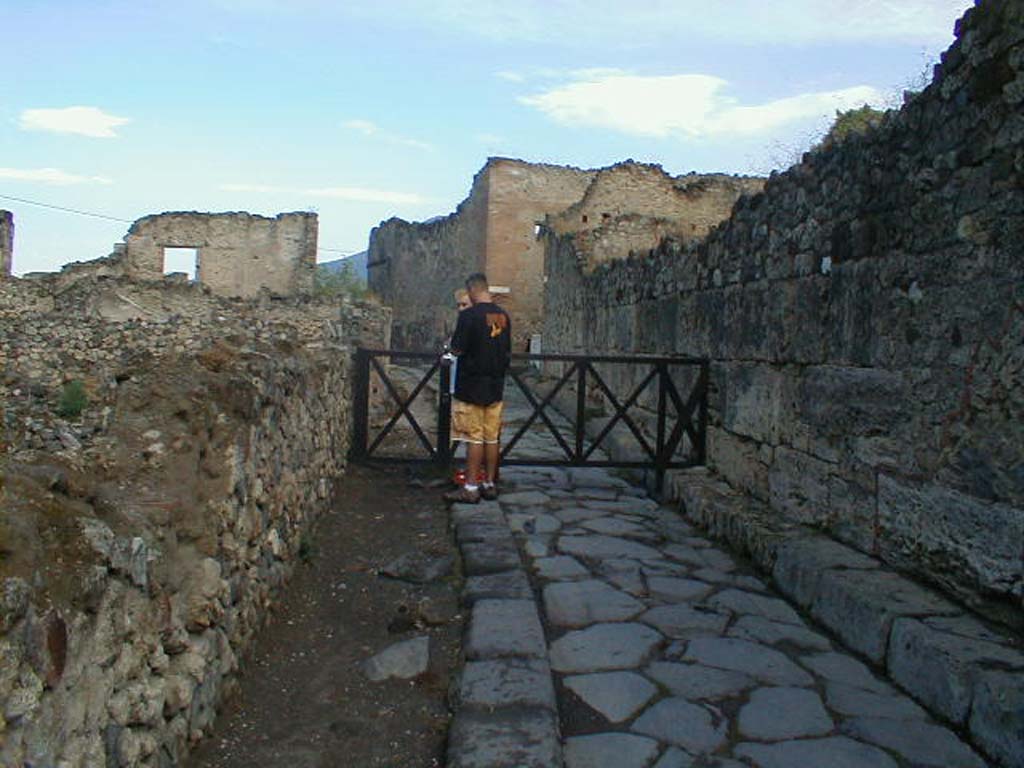 VII.16 on left of Vicolo del Gigante, Pompeii. September 2004. Looking north along side wall of VII.7.11/12.