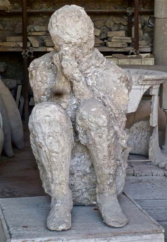 VII.7.29 Pompeii. May 2011. Plaster cast of a figure found near the latrine, perhaps crouching on the ground with his back against the wall of the east portico of the Palaestra at II.7. Photo courtesy of Michael Binns.
According to Stefani, when this body was cast, he was found to be tipped forwards, huddled up and bent double on his knees, when restored he was placed in this position.
See Stefani, G. (2010). The Casts, exhibition at Boscoreale Antiquarium, 2010. (p.10)