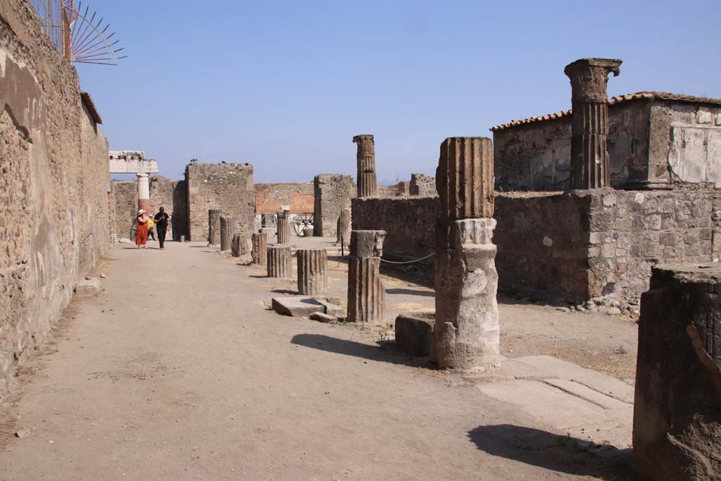 VII.7.32 Pompeii. September 2019. Looking east along north side of colonnade. Photo courtesy of Klaus Heese.
Cooke, Cockburn, and Donaldson wrote -
“At the end of the court, opposite the entrance, was a small chamber, which possesses an invaluable picture of Bacchus and Silenus, the former holding the thyrsus in one hand and a vase in the other; Silenus appears with his lyre instructing the god. A small niche is in the wall, apparently for the reception of a statue or lares.”
See Cooke, Cockburn, Donaldson: Pompeii, Pt 1, 1827, (p.55)
According to Garcia y Garcia –
“Because of the bombardment in 1943 there was much damage to the temple: it was hit by two bombs during the night of 13th September, when the west portico with the demolition of part of the stylobate, four columns and the demolition of an 8m part of the perimeter wall to the west were hit. Hit again by a successive incursion, there followed the demolition of the north-east corner of the portico with fallen and partial loss of the IV Style painted plaster; the felling of part of the north perimeter wall, of four columns from the north portico and of the stylobate that surrounded the temple. The rear room to the north of the portico was completely destroyed. The painting of Bacchus and Silenus is now in the Naples Archaeological Museum.”
This small room, perhaps used by the priest, became to be known as the chamber of Bacchus.
See Garcia y Garcia, L., 2006. Danni di guerra a Pompei. Rome: L’Erma di Bretschneider. (p.111-112).
