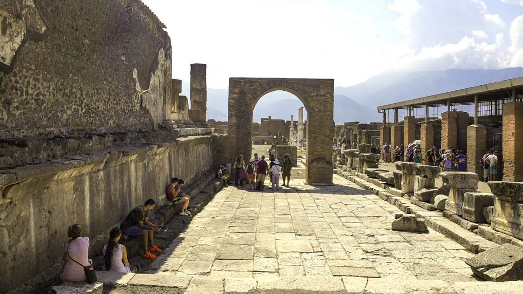 VII.8.1 Pompeii. August 2021.
Looking south with west wall of Temple of Jupiter, on left, towards Arch of Augustus in north-west corner of Forum. Photo courtesy of Robert Hanson.
