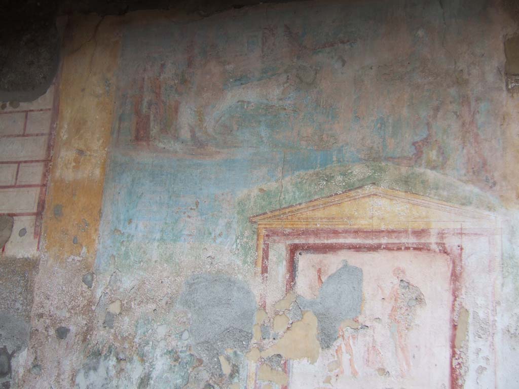 VII.9.33 Pompeii. December 2005. Remains of large landscape painting on west wall, with the lararium painting below.
According to Jashemski, this site, excavated in 1822-23, was badly damaged by the earthquake or at an earlier period.
It had 3 rooms on the right (north).
On the left a door to the adjacent shop, and behind this, a dormitory, a latrine, a stairway leading to the upper floor, and a kitchen.
Fiorelli believed the site was used as a caupona.
The area between the rooms on the right and on the left is difficult to explain.
The rear wall opposite the wide entrance was decorated with a landscape with a lararium painting in the lower right.
The shrine was framed by a twining vine shoot on which various birds were perched.
The excavators expected the structure underneath the aedicula to be an altar, but it was found to be a fountain filled with lapilli and other volcanic debris.
The mosaic pavement around the fountain pictured a variety of dolphins and geese.
The mosaic, however, had been damaged by later construction.
It would appear that the area in which the fountain stood was once a garden. It may have lasted, in part, as a garden – in part, as a courtyard.
She pointed out that Boyce called the area of the Lararium “a kitchen”.
See Jashemski, W. F., 1993. The Gardens of Pompeii, Volume II: Appendices. New York: Caratzas. (p.189).