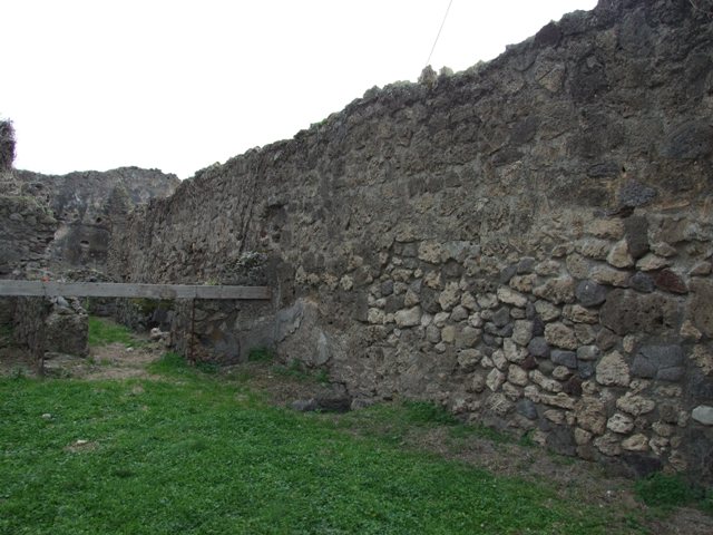 VII.12.13 Pompeii. December 2004. Lararium nNiche on east wall in front of oven in south east corner. Two mills can be seen in the bakery area to the right of the oven.