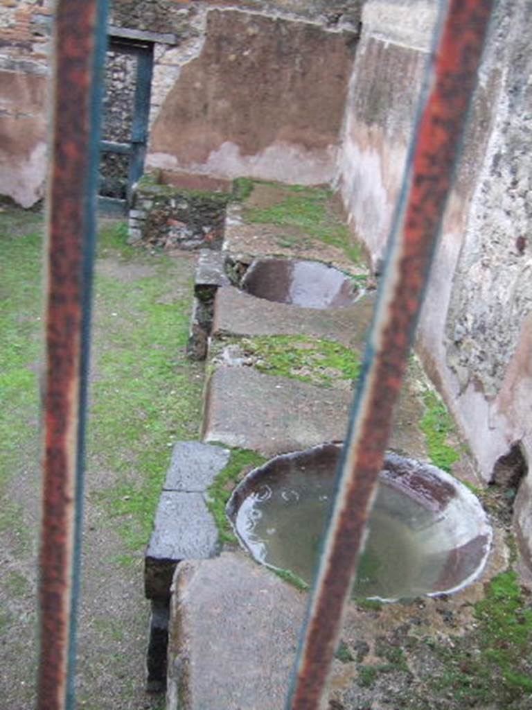 VII.12.17 Pompeii. December 2005. South side. View from VII.12.21 of two round water basins in podium.