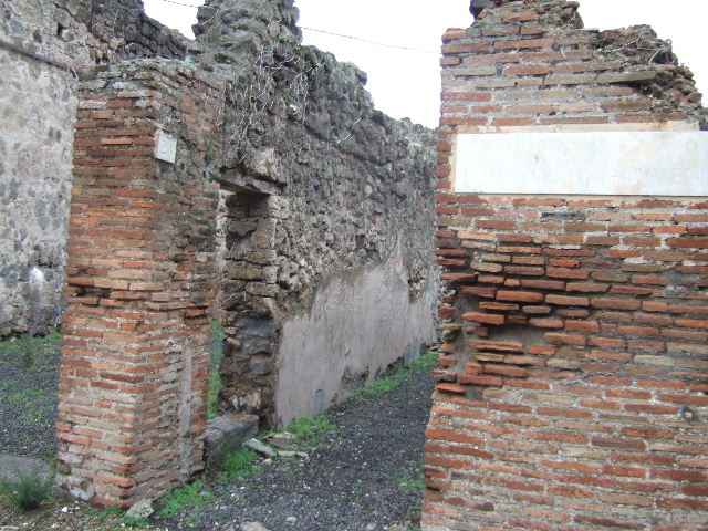 VII.12.26 Pompeii. December 2005. Fauces leading to small garden area at front of house. According to Jashemski, the garden at the front of the house was reached by a long corridor. It was enclosed on the north and east by a portico. This was supported by two columns and one engaged column which were joined by a low masonry wall. It had an entrance to the garden on both the north and east sides. According to Fiorelli, half the garden was cultivated, half of it was paved to provide a passageway to the portico. The triclinium on the north side had a fine view of the garden. A large window in the south wall of the garden gave light to the shop on the other side.
See Jashemski, W. F., 1993. The Gardens of Pompeii, Volume II: Appendices. New York: Caratzas. (p.196)