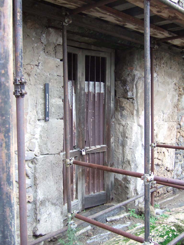 VII.12.28 Pompeii. December 2005. Entrance doorway.
According to Boyce, in this house was found a ruined lararium painting done on a white background.
He said it was not certain in which room the painting was seen.
Fiorelli placed it in the atrium, the Ann. Inst. and Helbig placed it in the kitchen.
In the west wall of the kitchen, a rectangular niche can be seen. Perhaps the painting was seen on the wall beside this niche?
Above the coils of a single serpent (female, according to Helbig) stood a Lar in green tunic and brown pallium.
The corresponding serpent and Lar on the other side had disappeared.
Helbig, 38; Ann.Inst., xxxv, 124, X; Fiorelli, Scavi, 105, No.17, Fiorelli, Descr., 291.
See Boyce G. K., 1937. Corpus of the Lararia of Pompeii. Rome: MAAR 14. (p.71, no.322)
According to Giacobello –
The plastered arched niche was found in room (h) on the west wall, the room having decoration in the Fourth Style.
See Giacobello, F., 2008. Larari Pompeiani: Iconografia e culto dei Lari in ambito domestico. Milano: LED Edizioni, (p.292, no.C17)