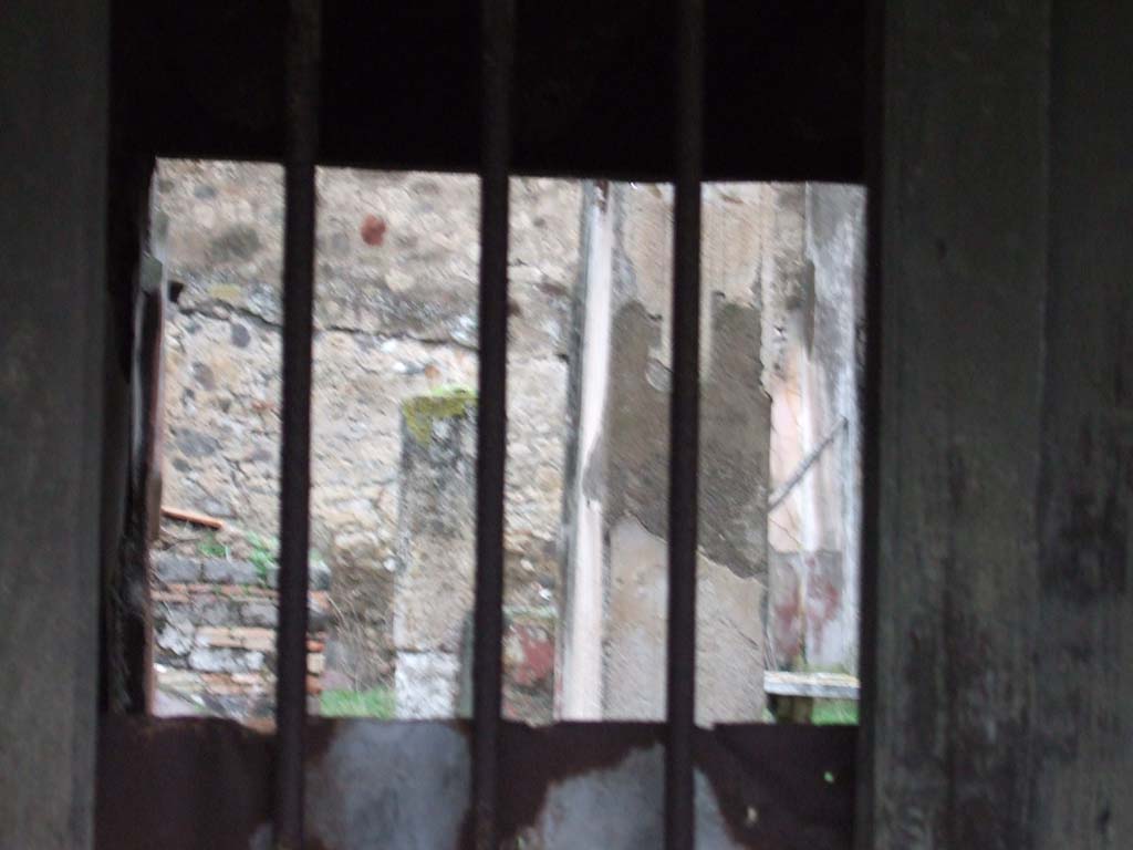 VII.12.28 Pompeii. December 2005. Looking north through doorway.
According to Pagano –
“Una scala di legno dava accesso al piano superiore, e questo slargavasi sulla via mediante un tavolato sorretto da travi e fornito di finestre che guardavano nella strada. Nel restaurarsi questo balcone, si era avuto mente a riprodurre con esattezza i legni che prima vi erando adoperati per sostenerio.
Entrando nella casa trovasi a sinistra la scalinata di legno che metteva al piano superiore. Viene in seguito un piccolo atrio dove ammirasi una graziosa fontana formata da un Puttino che regge colla sinistra una piccola colomba attualmente rotta, da cui sortiva un getto d’acqua che cadeva in una vaschetta.
Al di sotto del tavolino che vedesi alle spalle del Puttino, si osservano quattro chiavi di bronzo, per somministrare l’acqua in diversi punti della casa.
Il tablino ha un quadretto sulla parete a sinistra, che esprime Alceste ed Admete, allegoria dell’amor coniugale.”
See Pagano, N. (1881).Guida di Pompei, ed.9. (p.49-50).
(translation –
"A wooden staircase gave access to the upper floor, and this opened up onto the street with a floor supported by beams and provided with windows looking into the street. In restoring this balcony, it had been thought to reproduce exactly the woods that had previously been used to support it.
Entering the house, on the left we find the wooden staircase to the upper floor. Then came a small atrium where one could admire a pretty fountain formed by a Puttino/small boy/cherub that held in his left hand, a small dove (or shell) currently broken, from which a jet of water would have fallen into a tub.
Below the marble table we can see behind the Puttino, four bronze keys were observed, to administer water at different points of the house.
The tablinum had a picture on the left wall, showing Alcestis and Admetus, an allegory of marital love.")