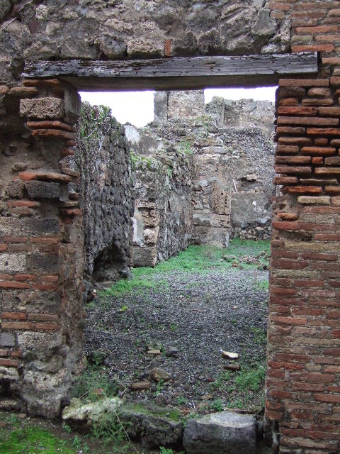 VII.12.31 Pompeii. Looking north through doorway to corridor. This used to contain steps to the upper floor, with a latrine underneath. Ahead at the rear was a cubiculum. On the left, a doorway leading to VII.12.32, on the right a doorway leading to VII.12.30.