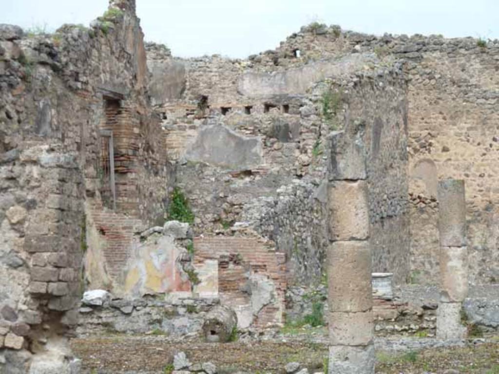 VII.13.4 Pompeii. May 2010.  North-west corner of peristyle with painted plaster, and rear triclinium room of VII.13.21. According to Boyce, on the west wall of the peristyle was a rectangular niche which originally appeared to have been fitted with an aedicula fa�ade but now gone. The interior walls were coated with white stucco and had delicate decorations in relief, including a cornice which ran around the top of the three walls.
See Boyce G. K., 1937. Corpus of the Lararia of Pompeii. Rome: MAAR 14.  (p.71 no.323)
