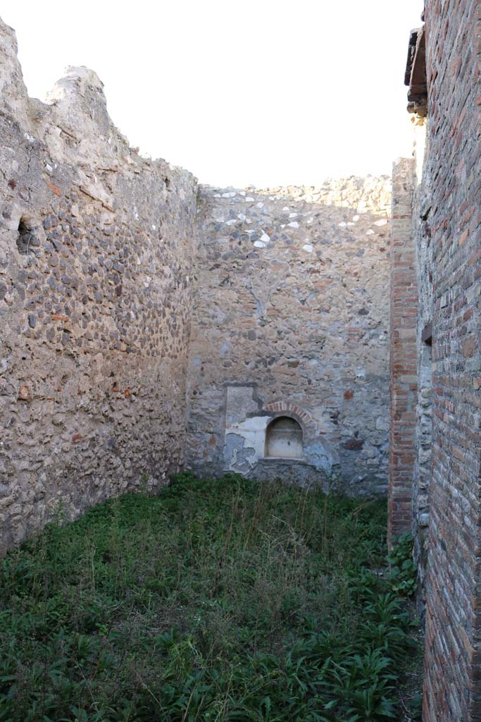 VII.15.8 Pompeii. September 2005. Looking west across tablinum, with window to oecus. The oecus also had a window overlooking the garden area, at the rear. According to Boyce, in the centre of the north wall of the garden area near the floor, was an arched niche. The wall around it was covered with a rectangular panel of white stucco. On this was an aedicula façade which was marked off with yellow and violet lines in low relief. The work was delicately executed but somewhat irregular.
See Boyce G. K., 1937. Corpus of the Lararia of Pompeii. Rome: MAAR 14. (p.72, no.332, Pl.6,2) 
