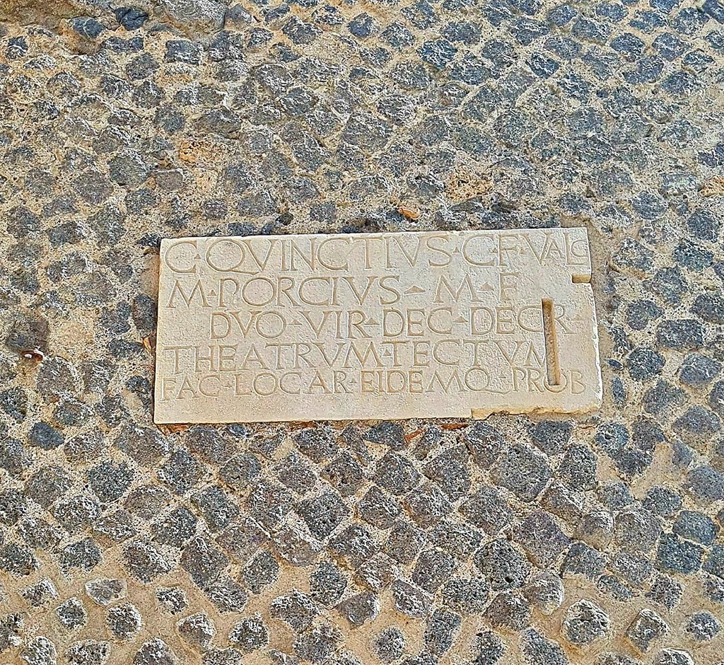 VIII.7.21 Pompeii. Pompeii. September 2024.
Dedication plaque on wall by the entrance from the large theatre to the small theatre. Photo courtesy of Giuseppe Ciaramella.