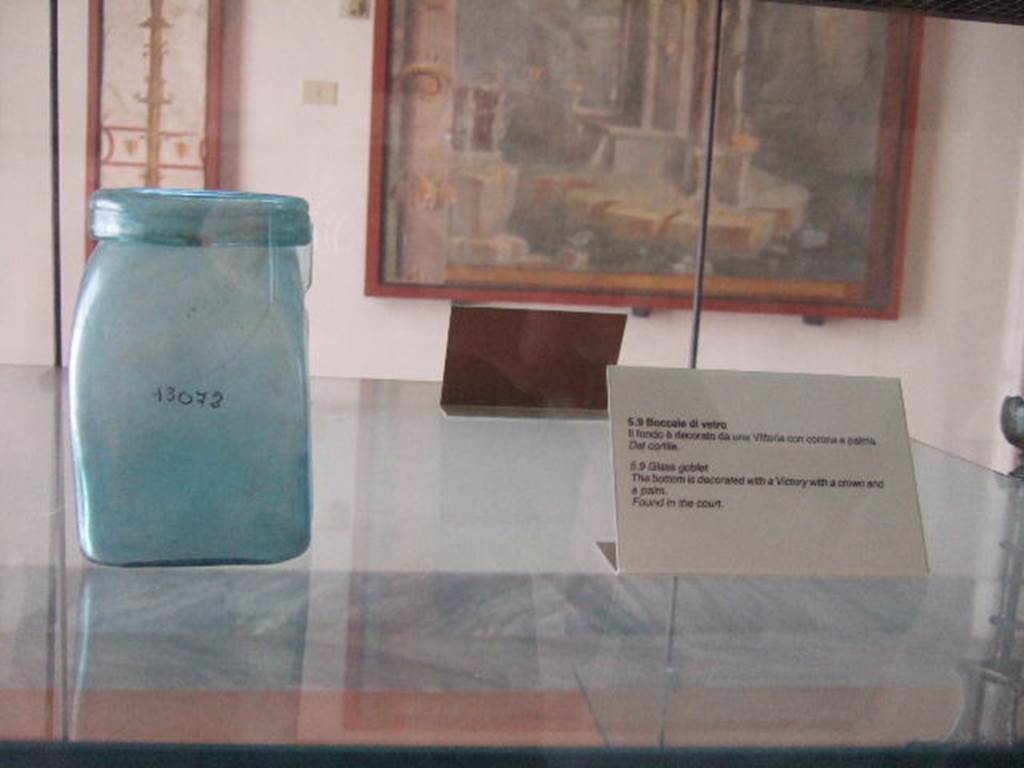 VIII.7.28 Pompeii. Square blue glass bottle with large rim, found in the courtyard. The bottom is decorated with the goddess of victory Vittoria who walks to the left bearing a crown and a palm tree.
Now in Naples Archaeological Museum. Inventory number 13072.