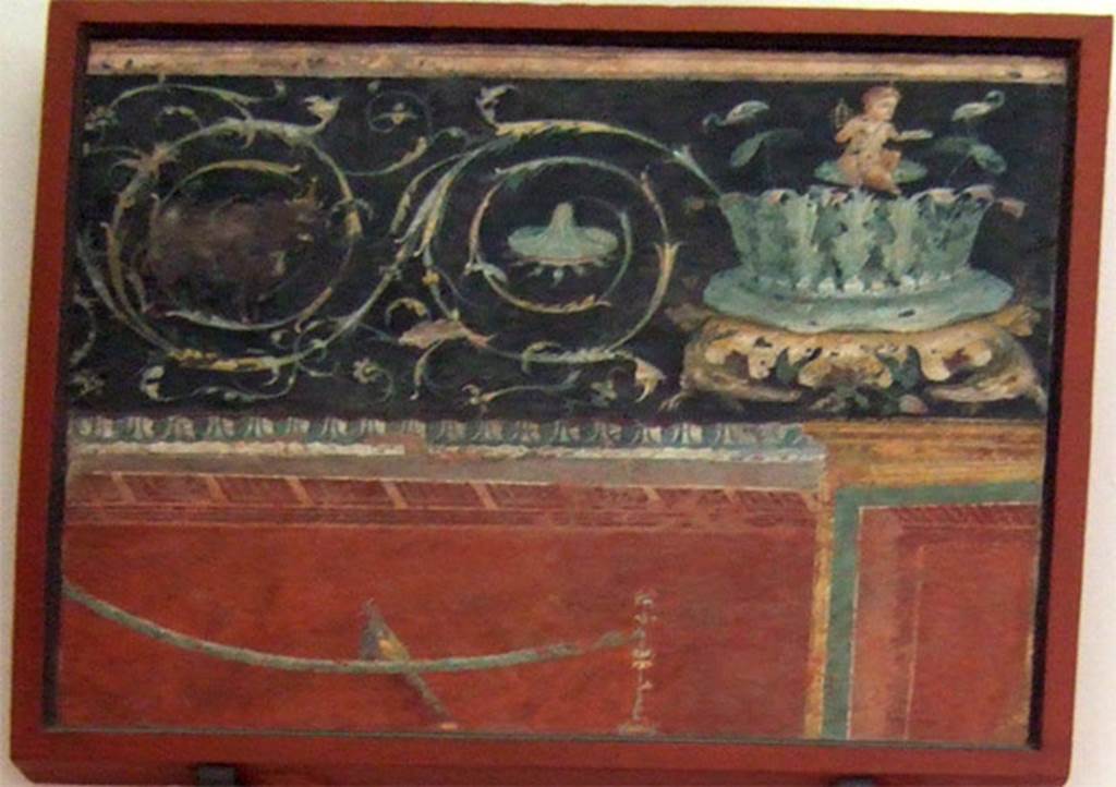 VIII.7.28 Pompeii. Found to the left of the shrine to Harpocrates. Central part of east wall.
Part of an architectural scene with two scrolls with an acanthus bush on the right supported by two crocodiles and on top of it sits a pygmy with a sistrum flanked by two ibis.
Now in Naples Archaeological Museum. Inventory number 8545.
